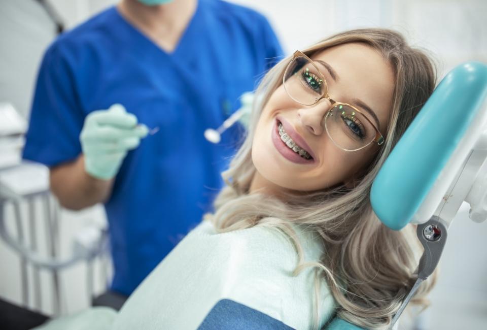 Uśmiechnięta osoba z aparatem ortodontycznym w gabinecie stomatologicznym